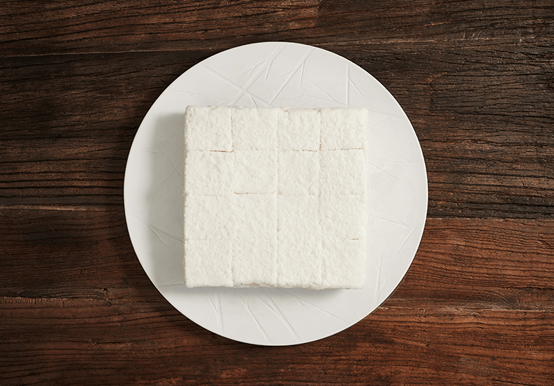 흰 접시에 놓인 백년화편 백설기 떡케이크